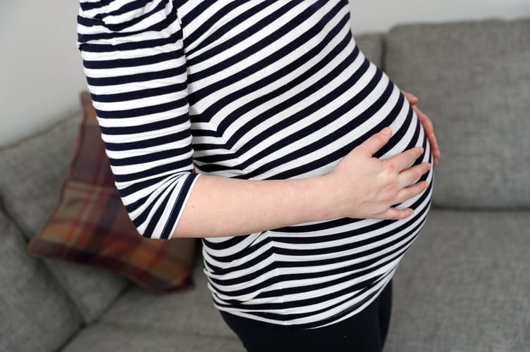 A pregnant woman holds her stomach.