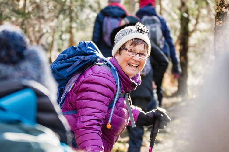 Member of a female club hiking for a body positivity campaign. The group are wearing back packs and waterproof clothing.