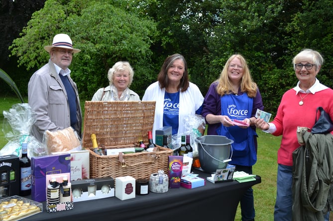 Di Pring, centre, chairman of the Crediton Friends of FORCE, with new member Sue Edwards, who ran the raffle table, pictured with customers buying raffle tickets.  Photo: Margaret Tucker
