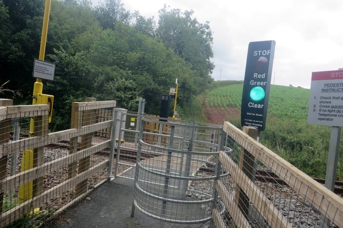 Showing that the railway line is clear, the green light stays on at the new pedestrian crossing over the Okehampton line at Penstone, the path going on up the hill.  SR 2730
