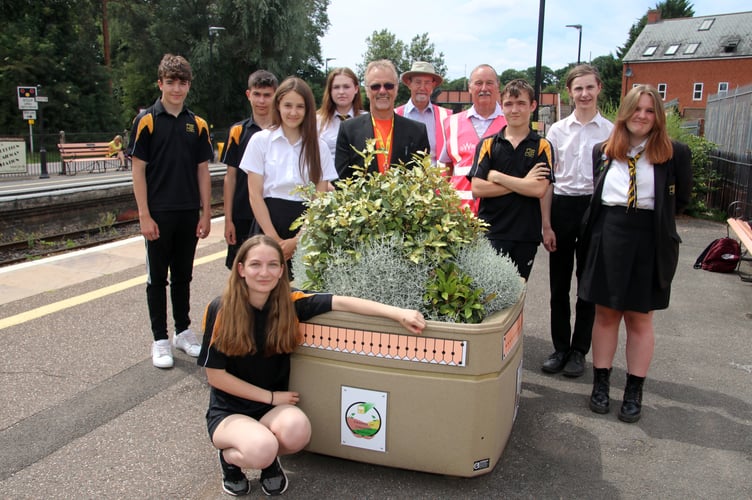 Reka Kucson, front, with her winning logo on one of the flower tubs with Mr Chudley, centre, Friends Alan Stewart and Cllr Mike Szabo and some of the other students who entered the logo competition. AQ 7356