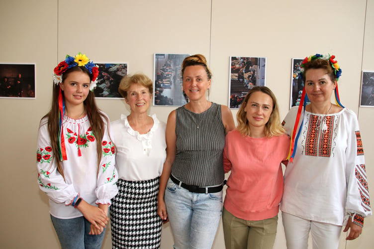 Some of the Crediton Ukrainian refugees with exhibition co-ordinator Cllr Mrs Natalia Letch, second left, in front of some of the exhibition images. AQ 8454