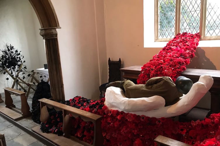 The inside of Dowland church with a life-sized soldier encircled by some of the beautiful handmade flowers.
