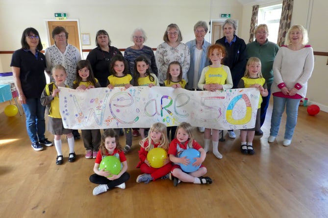 Pictured are current and former Cheriton Fitzpaine pack leaders with present day Brownies and Rainbows displaying the banner they have made.