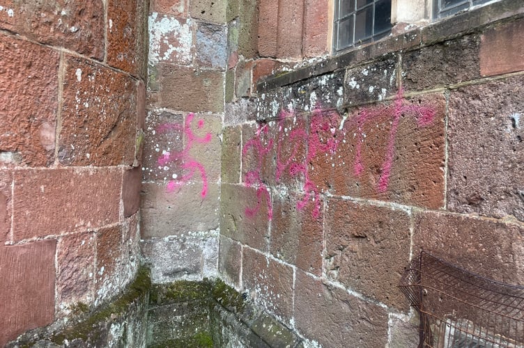 The spray paint on a wall at Crediton Parish Church.  AQ 2739