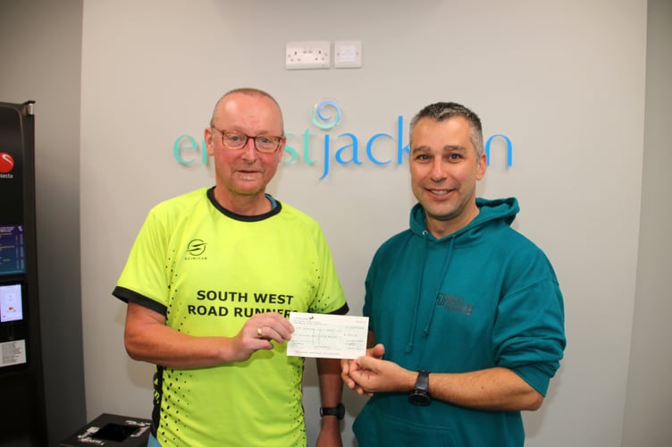 Lee Cusiak, from South West Road Runners, left, presents Martyn Slyfield, with the cheque for £250 for the 1st Crediton Scout Group. AQ 1540