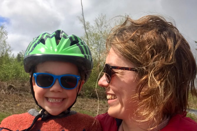 A woman holding her nephew and wearing a cycling helmet.