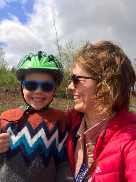 A woman holding her nephew and wearing a cycling helmet.