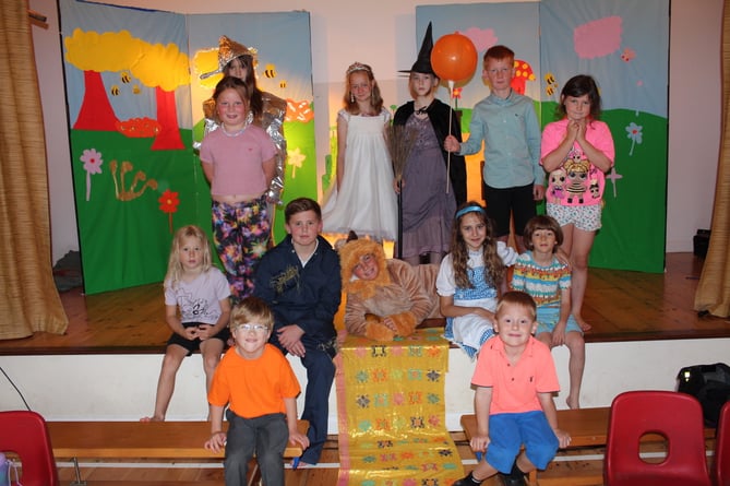 Main characters in 'The Wizard', the Lion lying across the Yellow Brick Road and a few Munchkins, seated beside the Scarecrow and Dorothy.  SR 8392