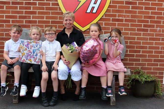 Mrs Merrett holds the flowers and book with some of the younger pupils.  SR 8419