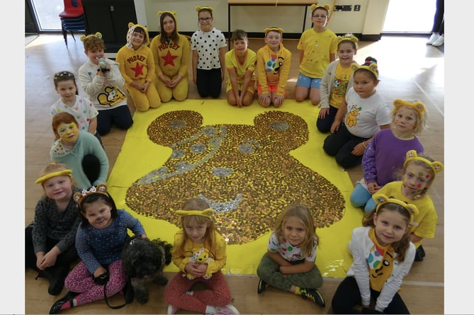 Some of the children from Landscore Primary School with the giant Pudsey head made out of coins for Children in Need.
