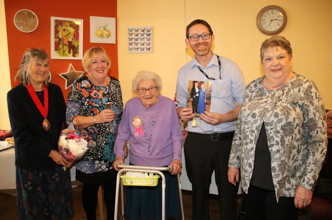 Iris Northcott, centre, with her daughters Jean, second left and Jill, right, with left, the Mayor of Crediton, Cllr Liz Brookes-Hocking and fourth left, Kenwyn Residential Home manager Danny Ruddock holding Iris’s birthday card from the King and Queen.  AQ 2903

