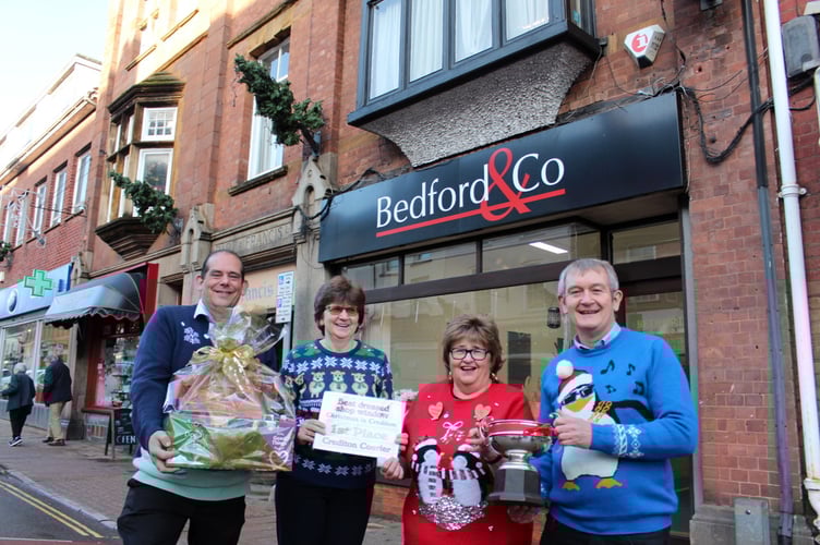 The Best Dressed Shop Window in Crediton last Christmas was by Bedford and Co. The Crediton Rose Bowl was presented by Alan Quick of the Courier, right, and was received by Clair Mann. Clair also received a hamper from Crediton Morrisons store manager Paul Callow, left and a certificate presented by the store’s community champion, Hazel Evely. SR 6724