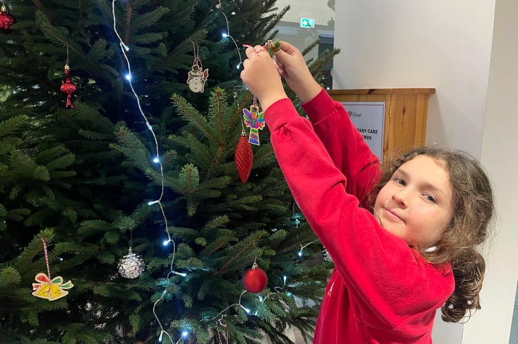 Decorating the Christmas tree in the foyer at Redlands Surgery. AQ 1580