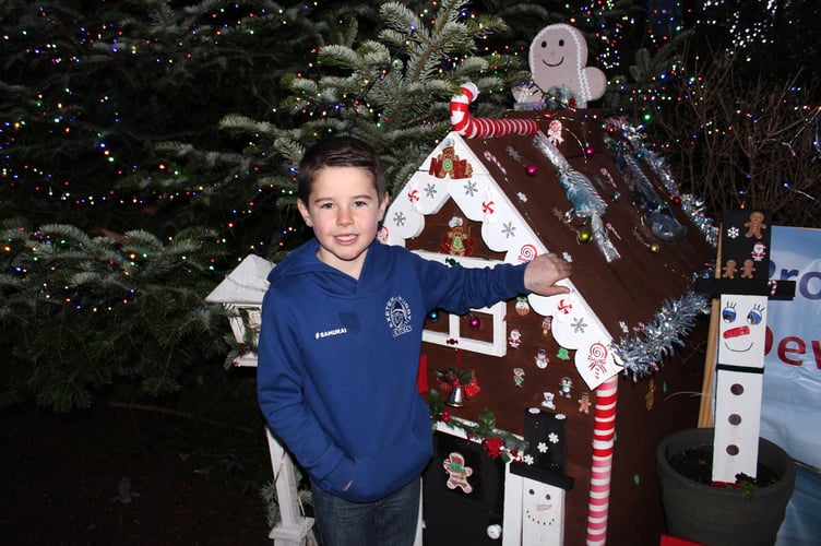 Austin beside the Christmas house under the big tree. SR 9245