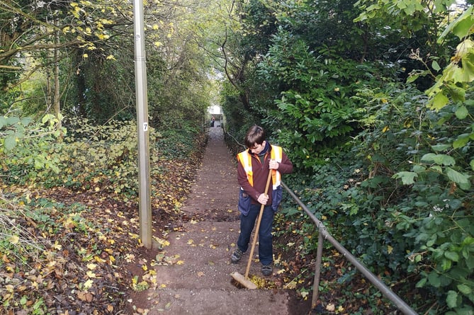 Sweeping leaves on steps in Crediton, one of the team from The Turning Tides Project.
