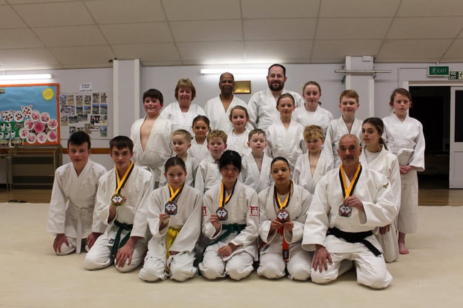 Students surround the medal winners, kneeling front with Sensei Jenny and Allen Carter at back, Sensei Neil at front with medal.  SR 9578
