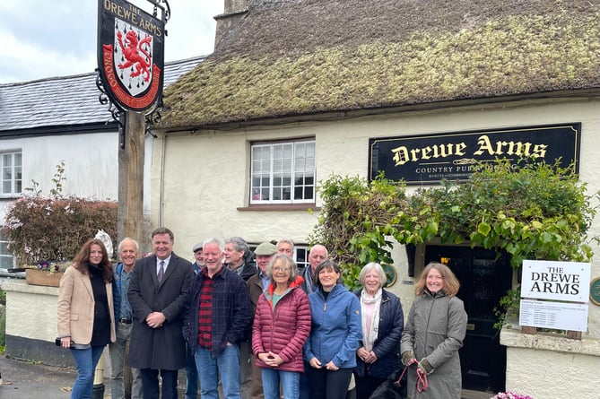 Mel Stride MP outside the Drewe Arms Pub with staff and customers.
