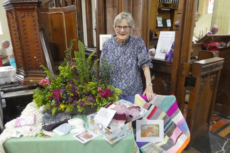 Mary Nunn with flowers, knitting and embroidery made by the Craft and Care Group