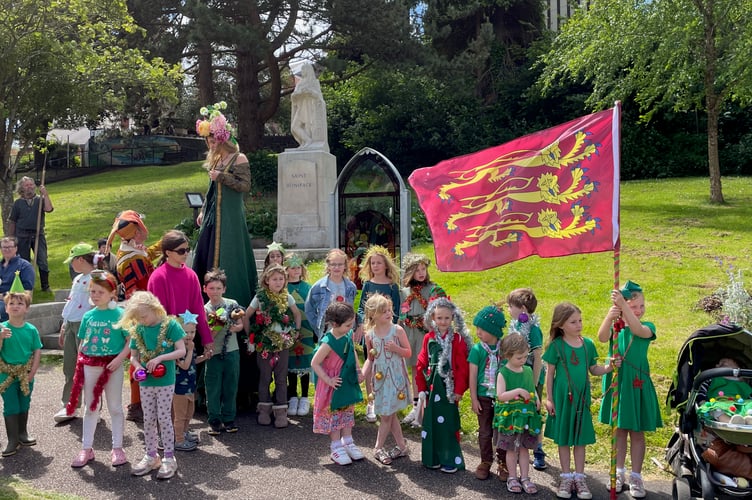 Children in Christmas tree costumes by St Boniface statue