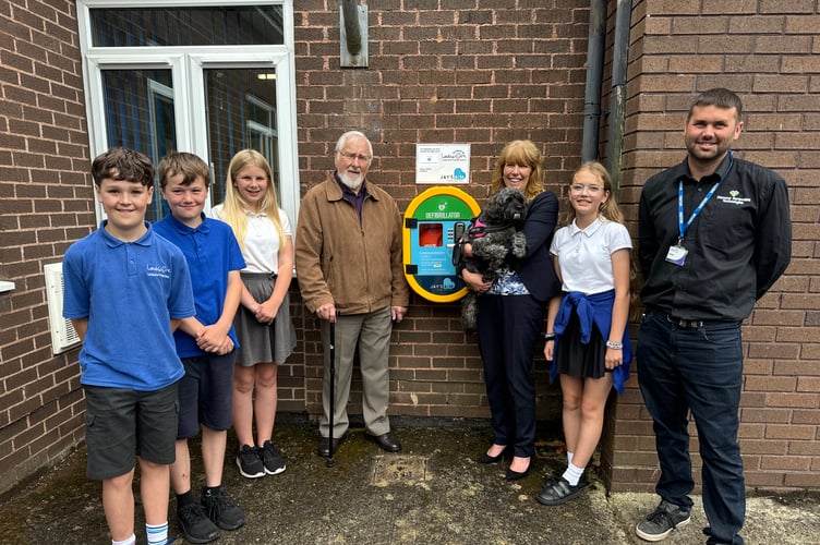 At the launch of the 24/7 public access defibrillator at Landscore Primary School, some of the Year 6 pupils with, from left, Robert Smalley, his daughter, the Headteacher Debbie Main with Coco the school dog and John Hill from Diamond Renewable Technologies. AQ 6881