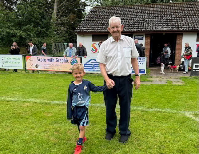 Dave Blanchford walking onto the pitch with one of his grandchildren.  AQ 7963

