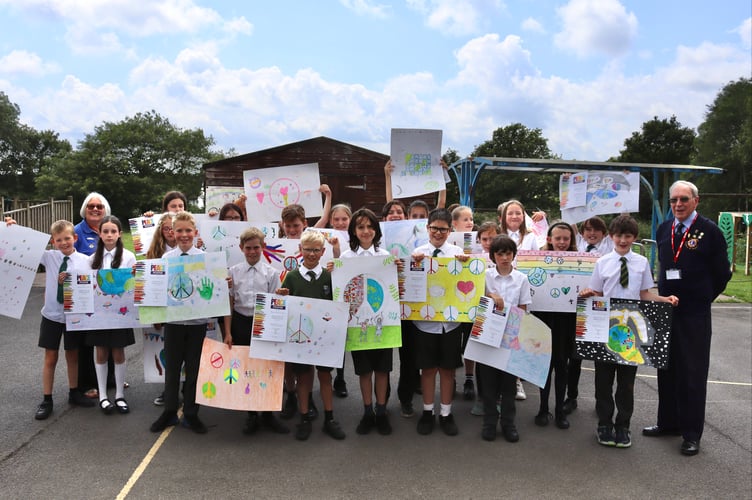 Copplestone pupils holding their peace posters with Ann Whitehouse and Eric Parkes of Crediton Lions Club