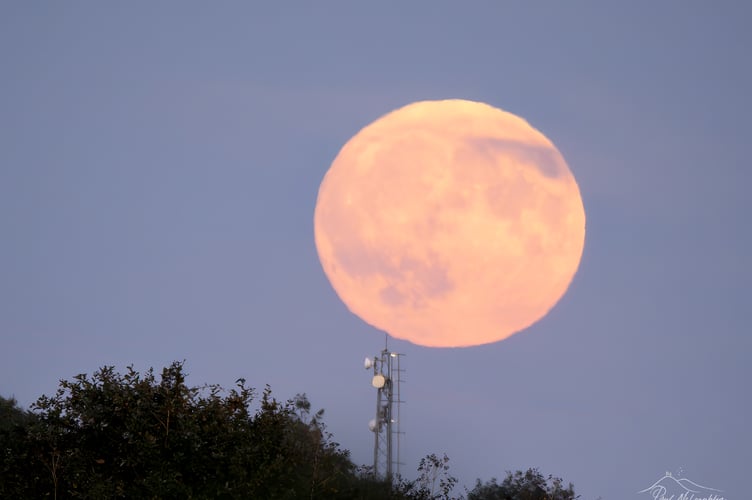 The harvest superman rising over the mobile telephone transmitter on George Hill in Crediton.
