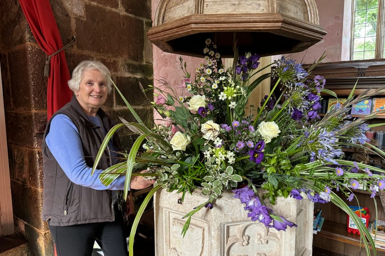 Valerie Pennington beside her display in the 15th century font at Colebrooke Church.  AQ 3981
