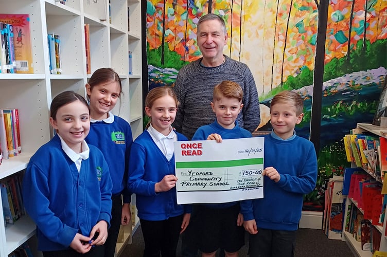 Jim from Once Read Bookshop presenting the cheque for £150 to Yeoford Primary School in Sue’s memory.