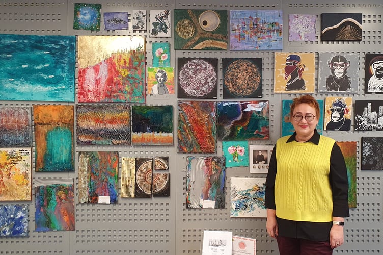 Iryna with her art exhibit at Crediton Library