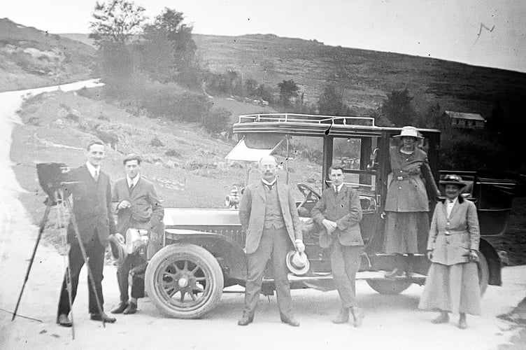 A group with a motorcar and camera on a tripod
