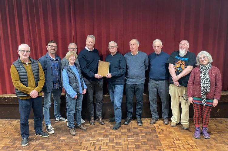 The Chair of Sandford Parish Council, Cllr Richard Ward, centre left, being handed the 1894 Annual Parish Meeting book still in use today by retiring Parish Clerk, Malcolm Vallance.
