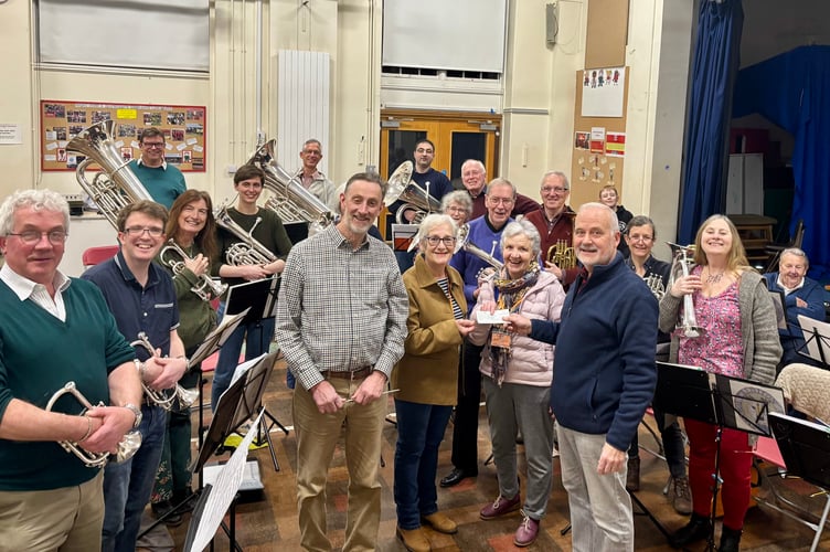 Crediton Town Band Chairman Chris Richards, centre right, recently presented, on behalf of Crediton Town Band, £363 to Crediton Playscheme, part of the proceeds raised at Carols in the Square.  The cheque was received by Playscheme representatives Bridget Ashplant, centre, and Margaret Gibson, centre right.
