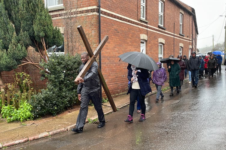 Volunteer carrying cross down Dean St