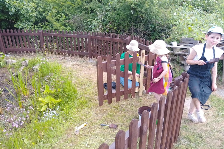 Painting fencing and a gate at Cheriton Fitzpaine Primary School.