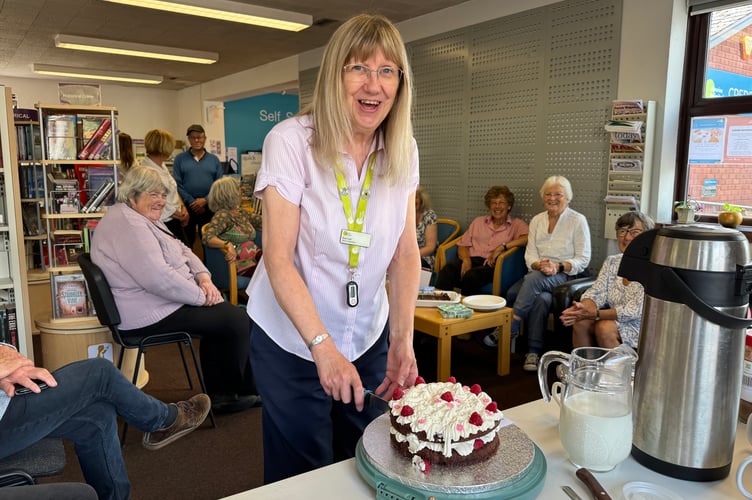 Sue cutting a celebration cake at Crediton Library AQ 2850
