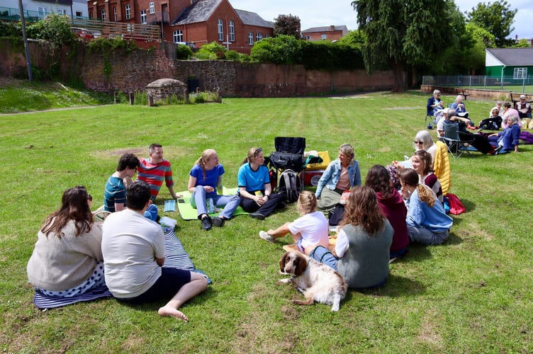 1 June 2025 Christians Together in Crediton Picnic in the Park 6x pic special Picnic-goers sitting in the sun (Will Goddard, Crediton Courier)