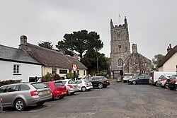 Square of Drewsteignton in May 2019, showing the Drewe Arms and Holy Trinity Church.