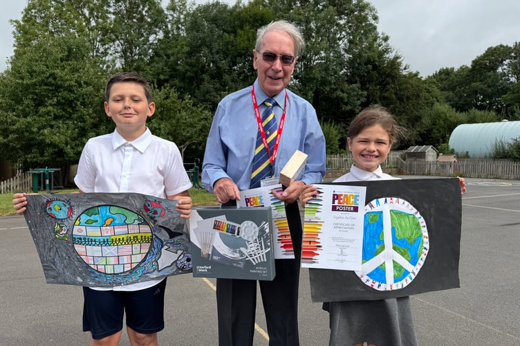 Copplestone winner Saul and runner-up Fern with their peace posters with Eric Parkes from Crediton Lions. AQ 6898