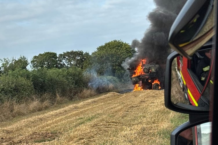 The combine harvester on fire as firefighters arrived.
