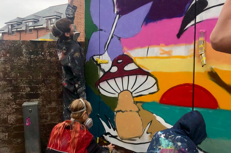 Young people painting the cabinet after their graffiti masterclass.