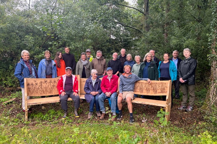 Linda and Colin, seated centre, with the bench commissioned for them in Sandford Millennium Green, with those who attended the presentation.