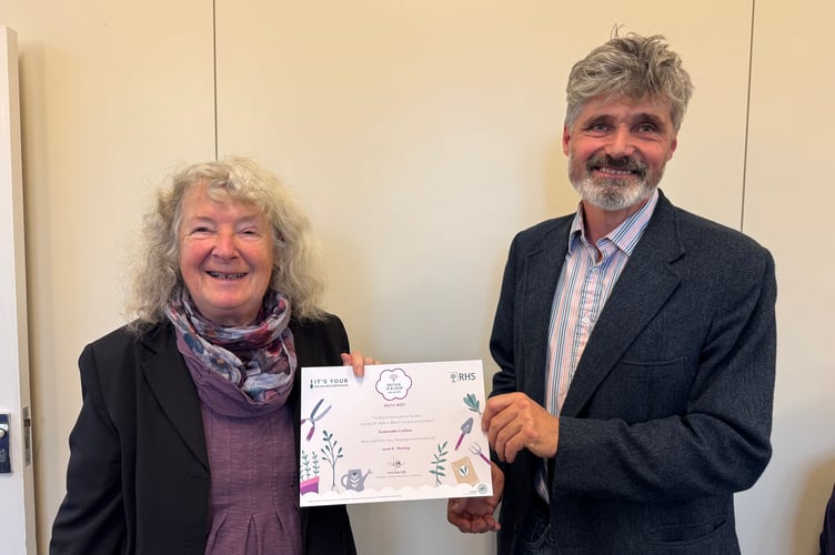 Esther Mann from Sustainable Crediton receives the Level 4 It’s Your Neighbourhood Thriving certificate from Crediton Town Councillor Giles Fawssett. AQ 7193