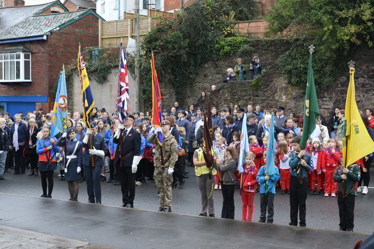 Cadets, scouts and others with standards at the war memorial as public looks on