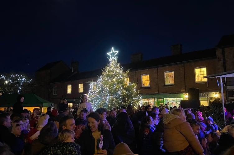 Crowds in Crediton Town Square with the illuminated 25-foot-tall tree