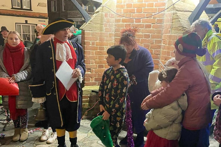 The Town Crier and George, centre, before he switched on the lights in North Tawton.