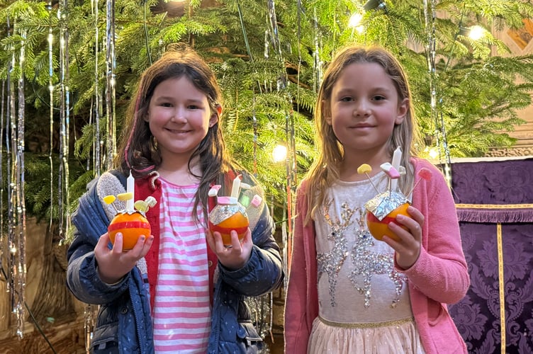 Two proud youngsters with the Christingles they made in front of the giant Christmas tree. AQ 0635
