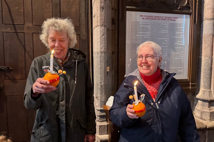 Two people with their lit Christingles in Crediton Parish Church.  A 0698
