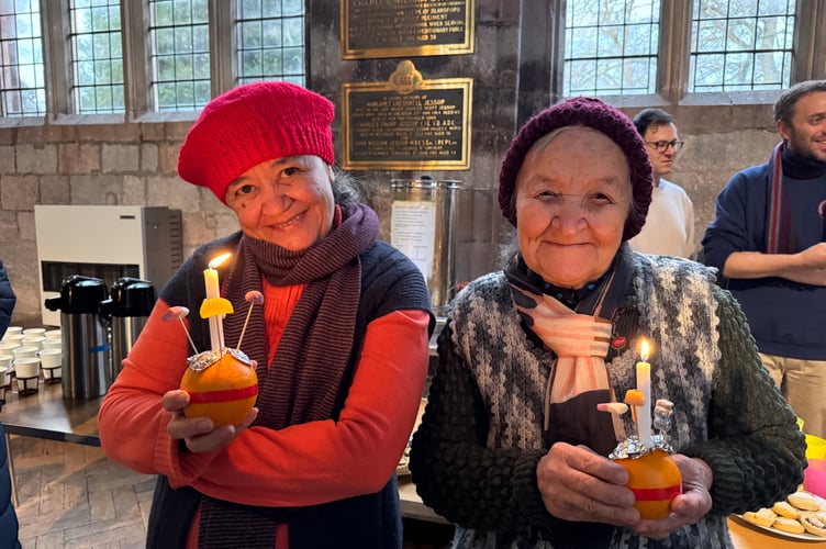 Two people with their lit Christingles during the service.  AQ 0703
